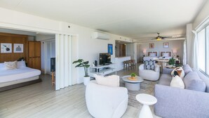 A modern living room with a sofa set, a TV, and a dining area with a table and chairs. - Two Bedroom Condo Overlooking Ala Wai Boat Harbor by RedAwning (Honolulu)