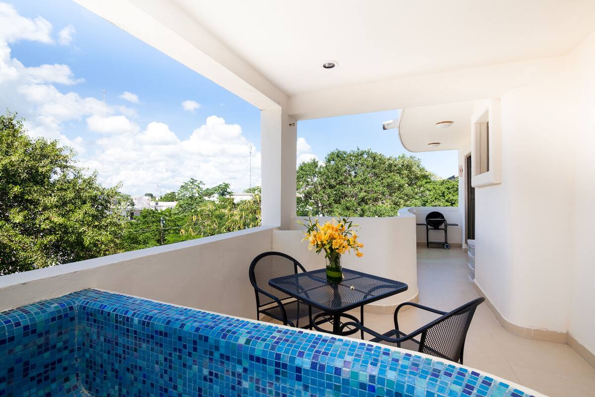 A balcony with a tiled pool, a table with chairs, and a vase of flowers.