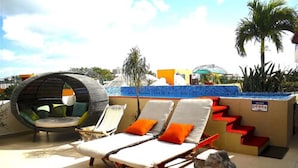 A rooftop pool area with lounge chairs and a hanging chair. - Condominio La Dolce Vita (Playa del Carmen)