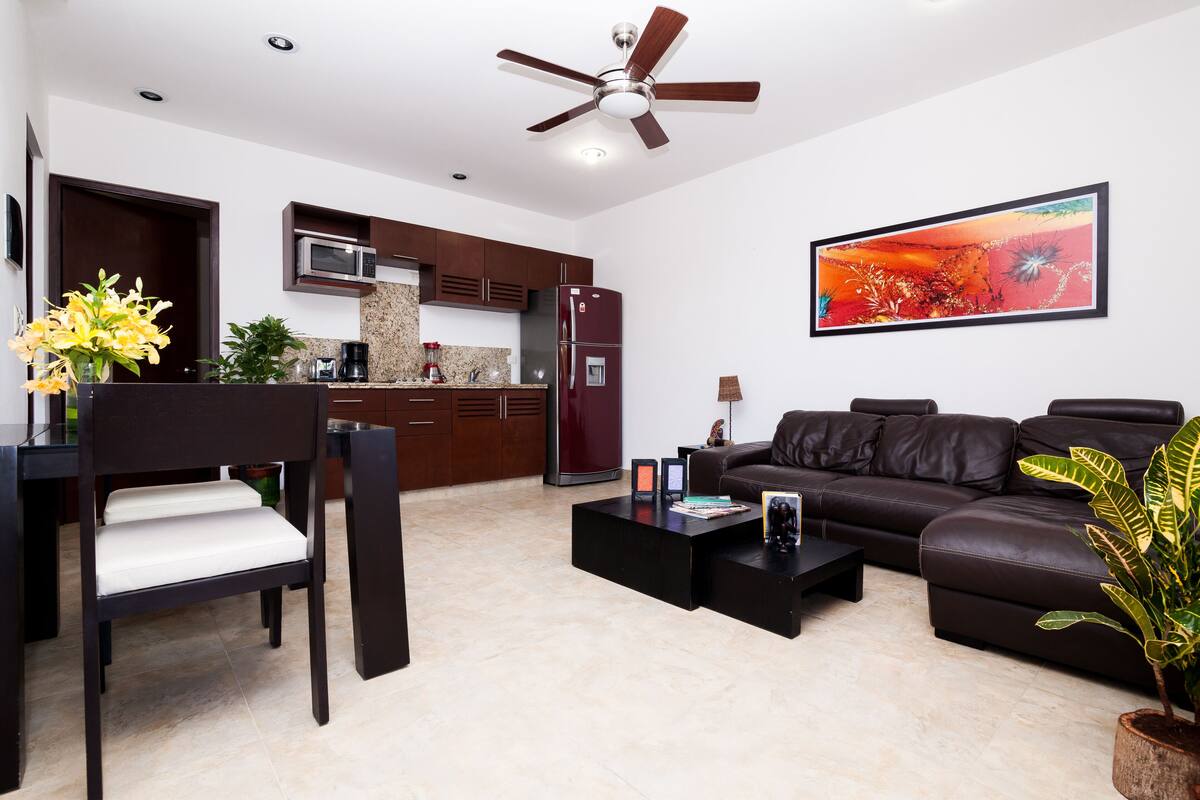 A modern living room with a sofa, coffee table, and a dining area with a chair and table.