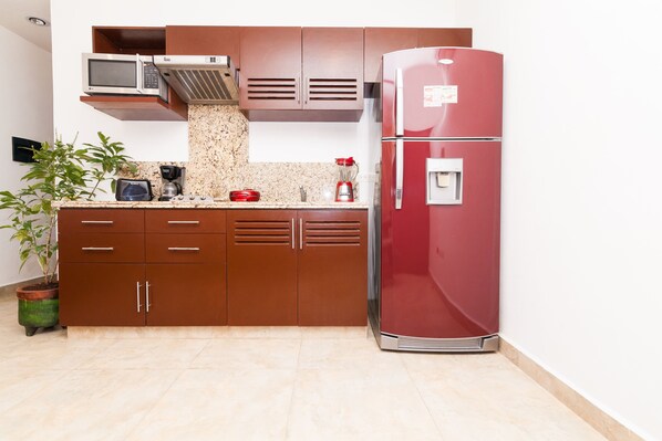A kitchen with a microwave, coffee maker, and refrigerator.