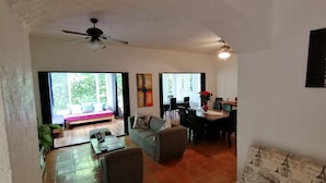 Amplia sala de estar con sofá, mesa de comedor y ventilador de techo.
