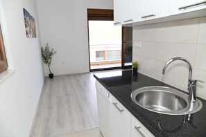 Una cocina moderna con un lavamanos de acero inoxidable, encimera negra y armarios blancos.