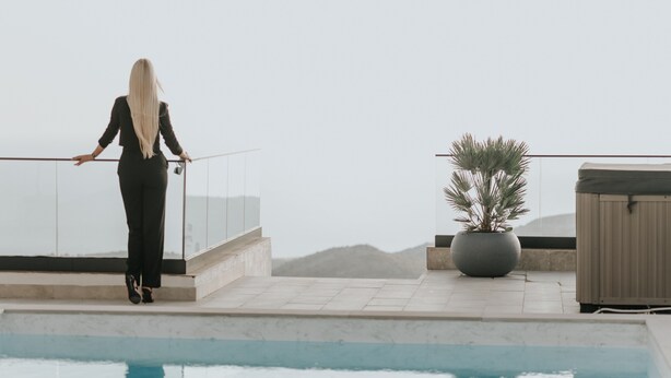 Eine Frau steht an einem Pool mit Blick auf Berge.