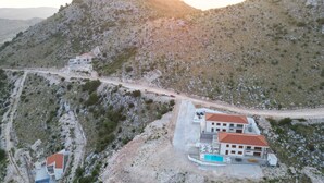 Eine gebirgige Landschaft mit einem Gebäude, das einen Swimmingpool und ein Gebäude mit rotem Dach zeigt.