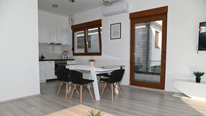 Une cuisine moderne avec des meubles blancs, une table à manger avec des chaises noires et une petite plante en pot posée sur la table.