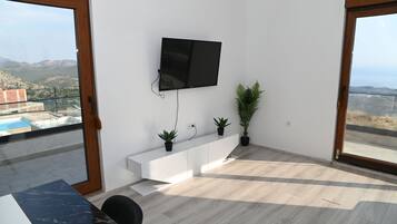 Uma sala de estar moderna com uma TV de tela plana na parede, um console branco e duas plantas em vasos.