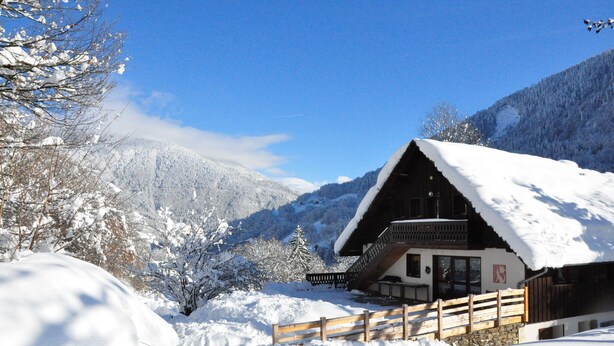 A wooden chalet with a balcony, surrounded by snow-covered trees and mountains. - Molliessoulaz barn with wolves (Queige)