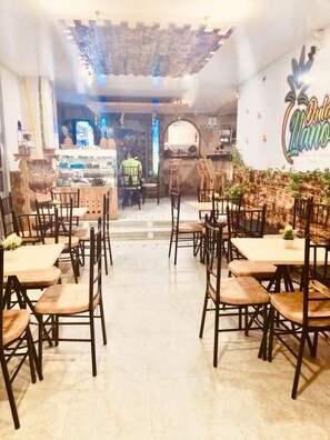A restaurant with wooden tables and chairs, a counter with a display case, and a wall with a sign.