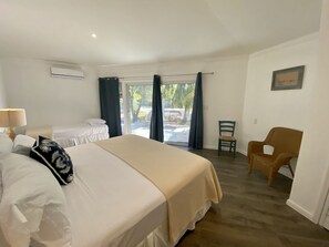 A hotel room with a bed, a chair, a desk, and a view of the outdoors.