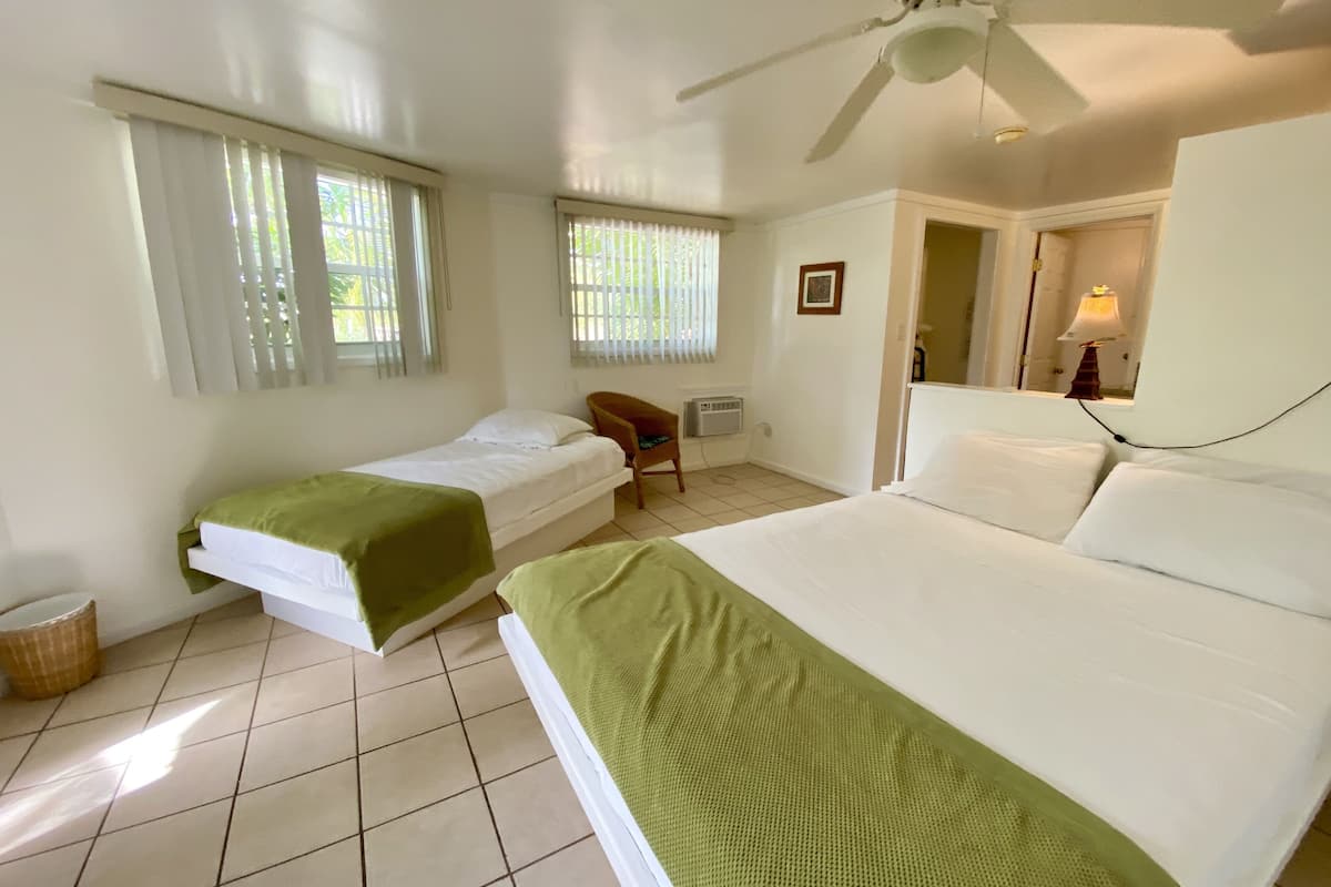 A hotel room with two single beds, a ceiling fan, and a chair.