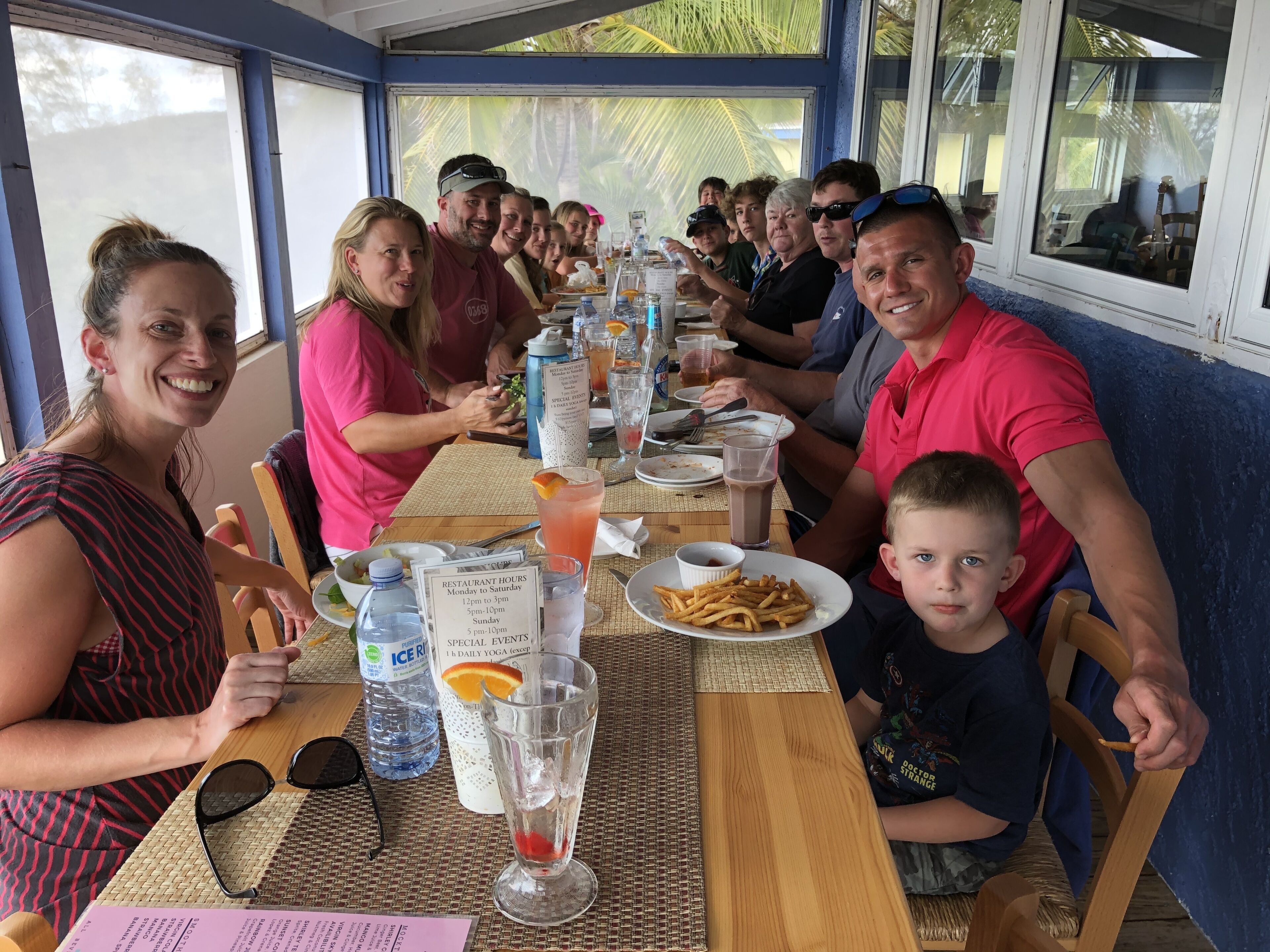 A restaurant with a long table set for a group, including plates of food, drinks, and a menu.