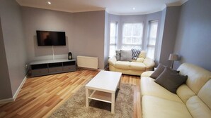 A living room with a sofa, a coffee table, a TV, and a radiator. - McDonald Road Apartment (Edinburgh)