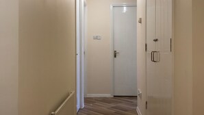 A hallway with wooden flooring, white walls, and a door at the end. - McDonald Road Apartment (Edinburgh)