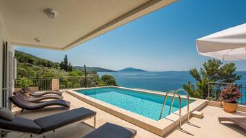 Een buitenzwembad, een verwarmd zwembad en ligstoelen