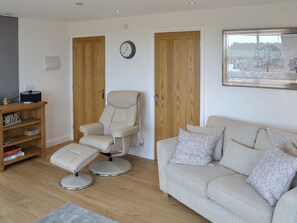 A living room with a sofa, a recliner, a wooden shelf, and a framed picture on the wall.