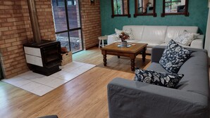 Una sala de estar con chimenea, un sofá blanco, una mesa de centro y vistas a través de una ventana.
