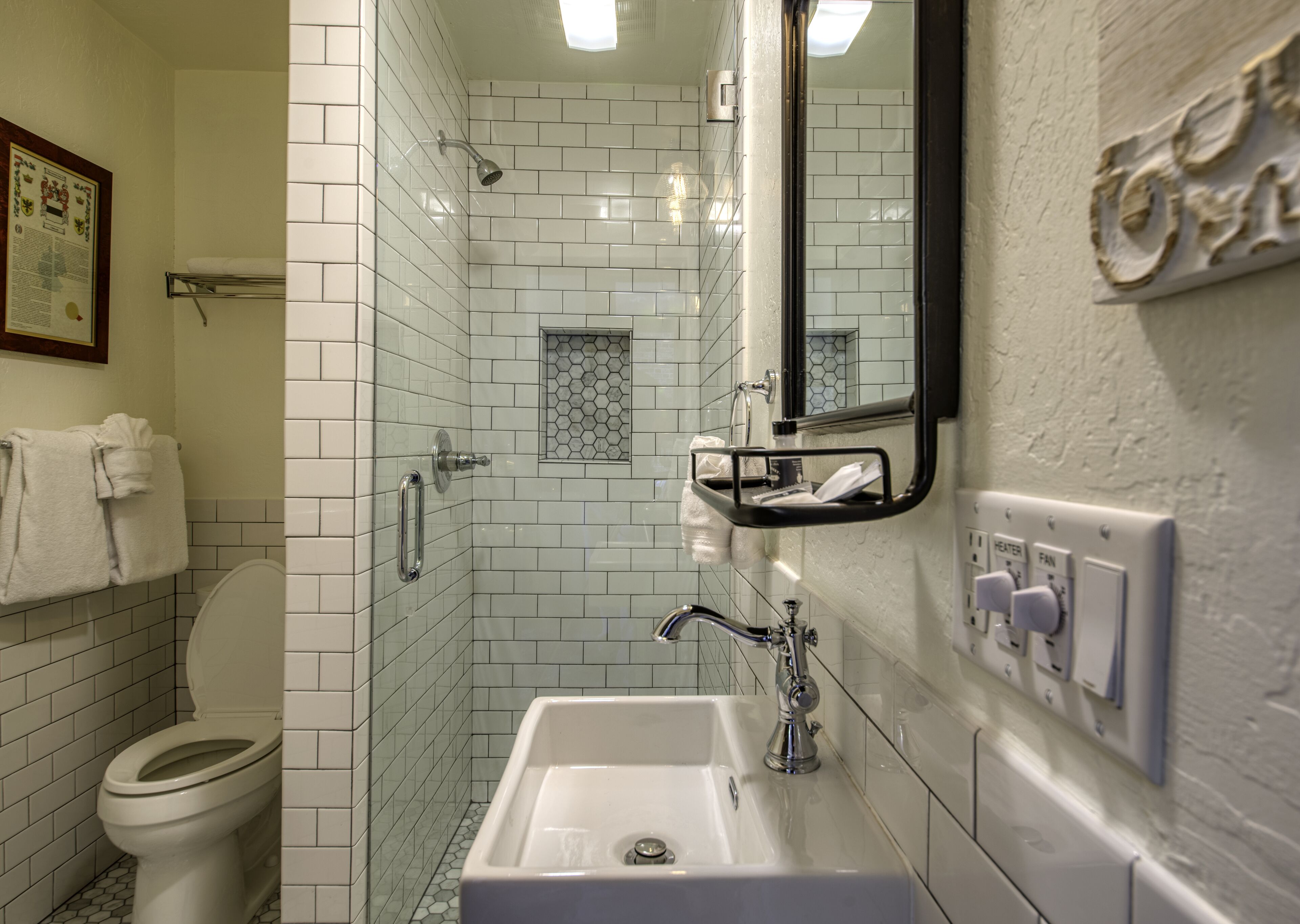 Un baño con inodoro blanco, lavamanos, ducha con puerta de vidrio y espejo.