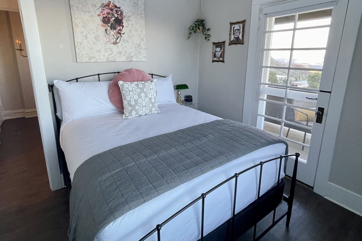 A bedroom with a bed, a ceiling fan, a window, and a door.