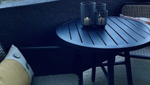 A balcony with a table and chairs, overlooking a scenic landscape.