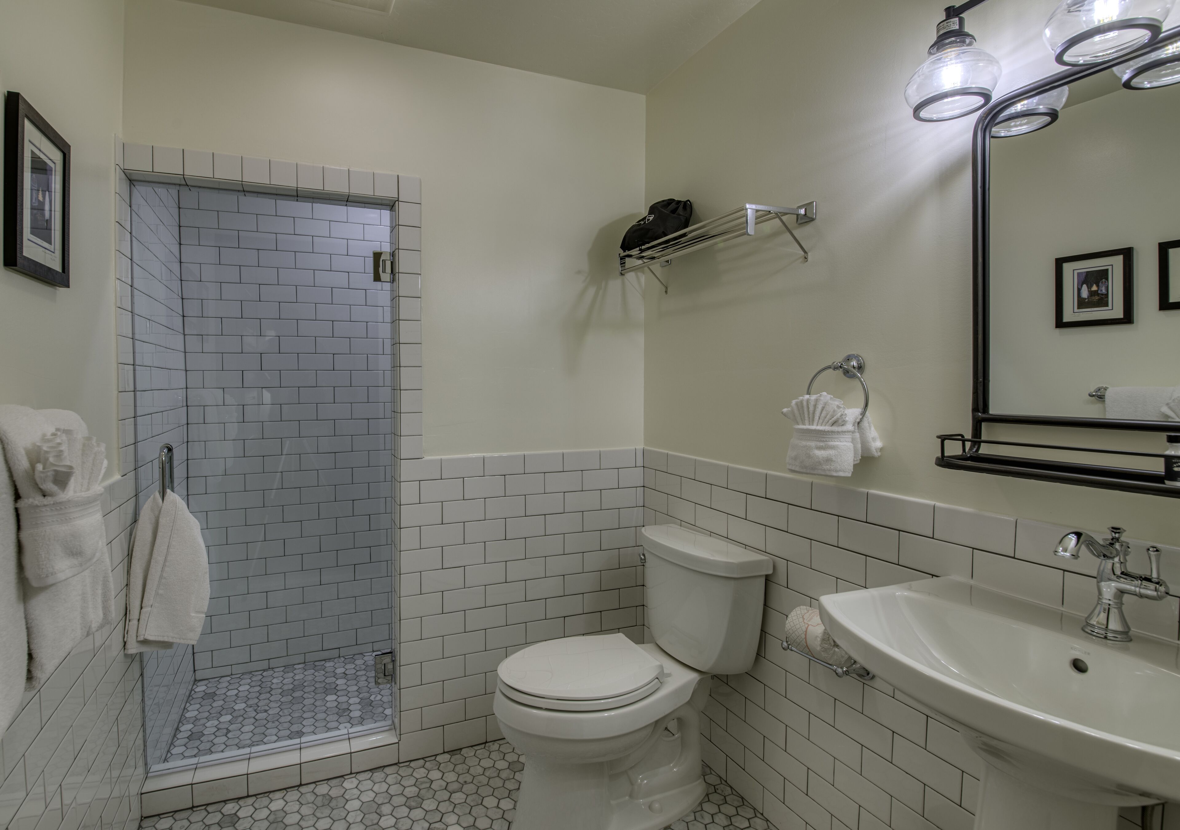 A bathroom with a shower, toilet, sink, and a mirror.