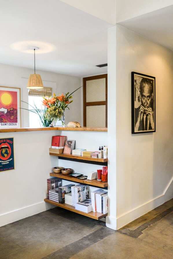 A hallway with a wooden bookshelf, a hanging light fixture, and a framed picture on the wall.
