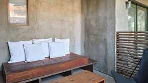 A cozy seating area with a wooden bench and cushions, a small wooden table, and a black chair. - Hotel San Jose (Austin)
