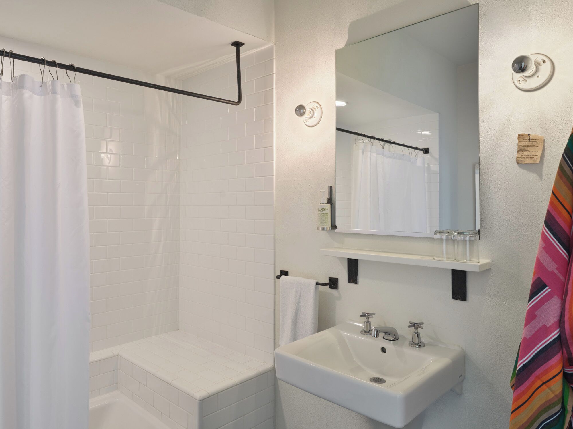 Een badkamer met een douche, wastafel en spiegel.