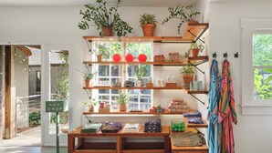 A cozy room with wooden shelves, a bench, and a window with a view of greenery. - Hotel San Jose (Austin)