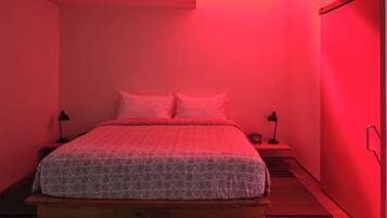 A bedroom with a bed, two bedside tables, a nightstand, and a wardrobe.