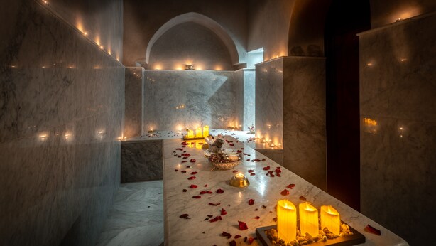 A marble-tiled corridor with candles and rose petals, leading to an arched doorway. - Palais Aix Kabaj & Spa (Marrakech)