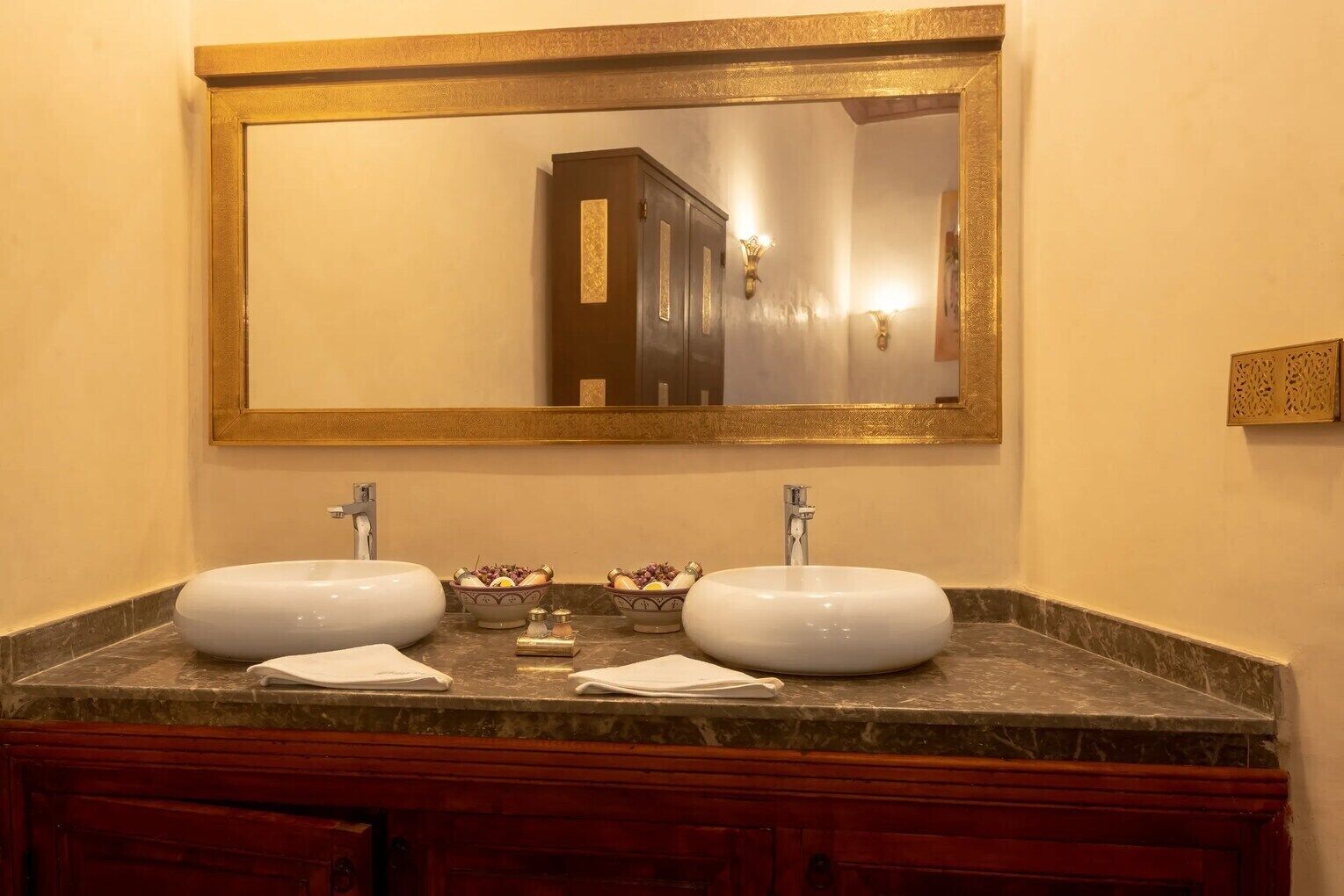 Un baño con dos lavamanos, un espejo grande y un mueble de tocador de madera.