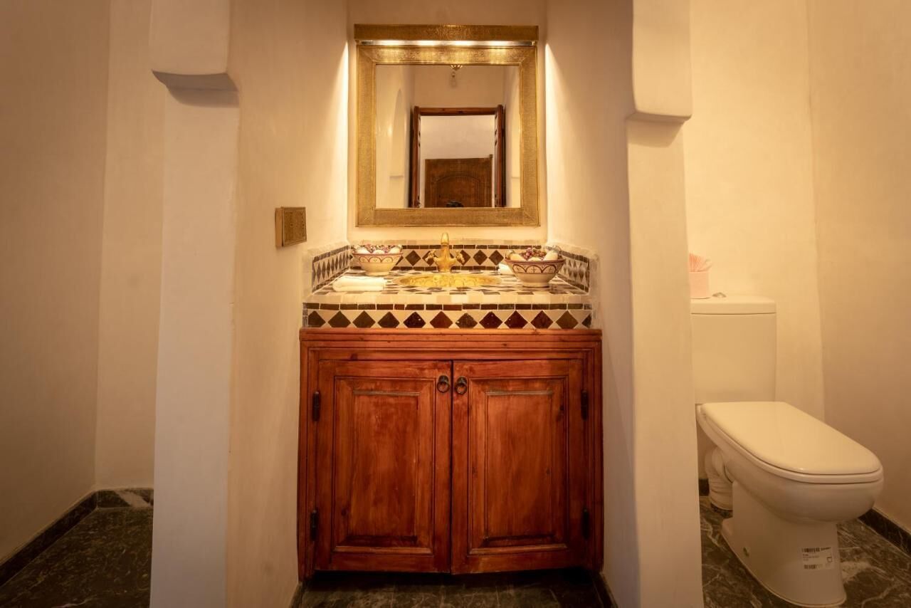Un baño con tocador de madera, un espejo grande y un inodoro.