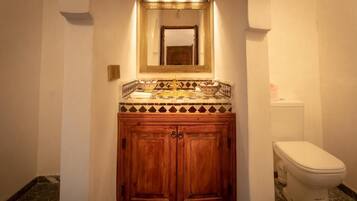 Un baño con tocador de madera, un espejo grande y un inodoro.