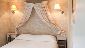 A bedroom with a large bed, two bedside tables, a nightstand, a chair, and two wall-mounted lamps. - Homerez - House in Saint-Martin-des-Entrées (Saint-Martin-des-Entrées)