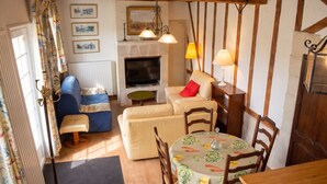A cozy living room with a television, sofa, and dining table. - Homerez - House in Saint-Martin-des-Entrées (Saint-Martin-des-Entrées)