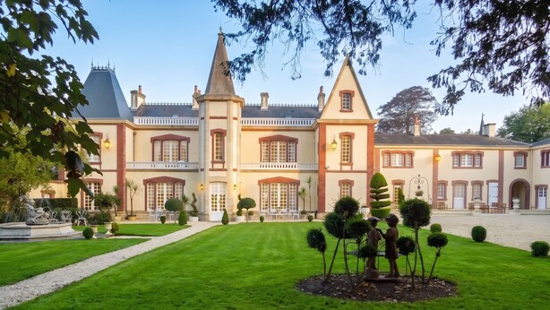 A grand building with a symmetrical facade, multiple chimneys, and a well-manicured lawn with a central sculpture. - Homerez - House in Saint-Martin-des-Entrées (Saint-Martin-des-Entrées)