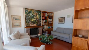 A living room with a fireplace, two sofas, a bookshelf, and a painting. - Villa Le Grotte on the sea Elba Island (Portoferraio)