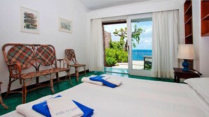 A hotel room with two beds, wicker furniture, a view of the sea, and a balcony. - Villa Le Grotte on the sea Elba Island (Portoferraio)