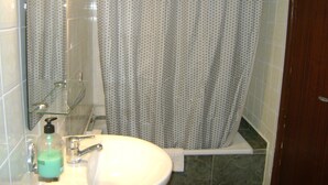 Un bagno con un lavandino bianco, un box doccia in vetro e una tenda da doccia fantasia.