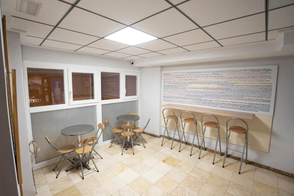 Een vergaderruimte met een whiteboard, opklapbare stoelen, een kleine ronde tafel en een betegelde vloer.
