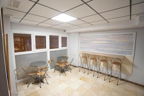 A conference room with a whiteboard, foldable chairs, a small round table, and a tiled floor. - Hostal Residencia Pasaje (Novelda)