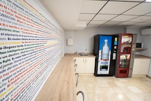A modern kitchen with a long counter and a water dispenser. - Hostal Residencia Pasaje (Novelda)