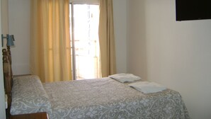 Una camera da letto con un letto, tende, una TV a parete e una finestra.