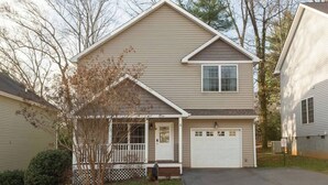 Une maison à deux étages avec un porche à l’avant, un garage et un petit jardin.