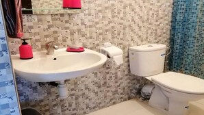 A bathroom with a white sink, toilet, and shower curtain. - Duplex feet in water in Taghazout 4563 (Agadir)