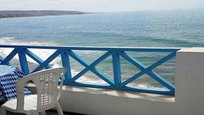 A balcony with a view of the sea, a white plastic chair, and a blue railing. - Duplex feet in water in Taghazout 4563 (Agadir)
