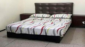 A bed with a striped bedspread and two pillows, a dark headboard, and a wooden nightstand to the right. - Duplex feet in water in Taghazout 4563 (Agadir)