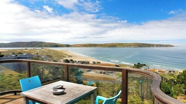 A wooden deck with a table and chairs overlooking a coastal view. - KH: Life is a Beach (Dillon Beach)