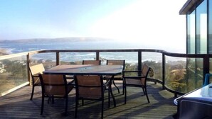 A deck with a table and chairs overlooking a coastal view. - KH: Life is a Beach (Dillon Beach)